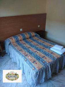 a bed with a blue comforter with a sign on it at Hostal Ribeiro Verín in Verín