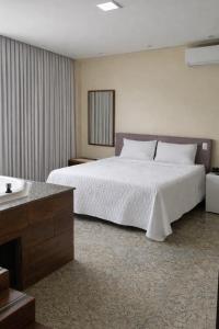 a bedroom with a large white bed and a sink at Hotel Pousada Bortolan in Poços de Caldas