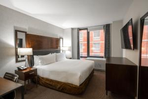 a hotel room with a bed and a desk and a window at Distrikt Hotel New York City, Tapestry Collection by Hilton in New York