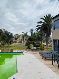 a swimming pool with green water next to a house at De Ocean Lane Guest House in Cape Town