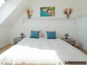 a bedroom with a large white bed with blue pillows at L'océanne in Équihen-Plage