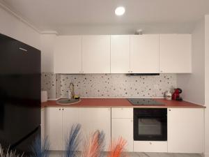 a kitchen with white cabinets and a sink at Damon Suite #NorthBucharest in Tunari