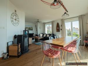 a dining room and living room with a table and chairs at L'océanne in Équihen-Plage