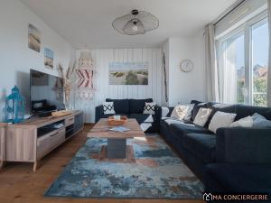 a living room with a blue couch and a table at L'océanne in Équihen-Plage