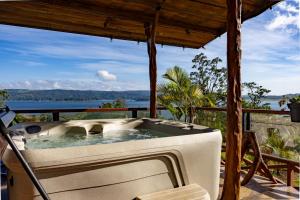 a hot tub on a deck with a view of the ocean at Lua Pele House - Arenal Volcano & Lake views in El Castillo de La Fortuna