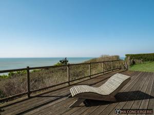a bench sitting on a deck with the ocean in the background at L'océanne in Équihen-Plage