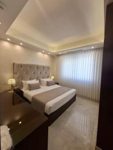 a bedroom with a large bed and a large window at Nadine Hotel Suites in Amman