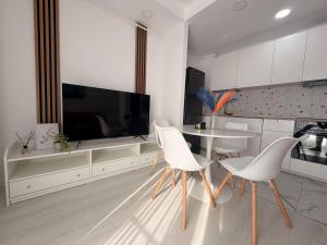 a white kitchen with a table and white chairs at Damon Suite #NorthBucharest in Tunari