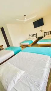 ein Zimmer mit drei Betten und einem Flachbildfernseher in der Unterkunft Hotel S Barbara in Mazatlán
