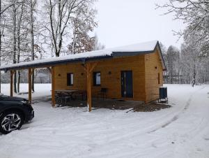 a wooden cabin in the snow with a car parked in front at PokojeS12 in Chełm