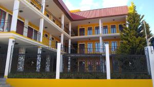 a yellow and white building with a black fence at HOTEL REAL DEL MONTE WOODs in Mineral del Monte