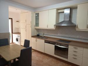 a kitchen with white cabinets and a table and a sink at Casa en vigo in Vigo