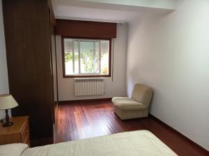 a bedroom with a bed and a chair and a window at Casa en vigo in Vigo