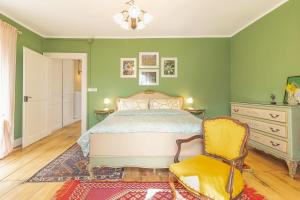 a bedroom with green walls and a bed and a chair at La Quiete del Mattino in Torre Pellice