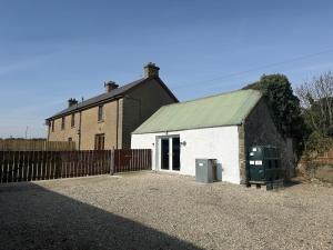 a small white building with a fence and a house at Dessie's in Magherasaul