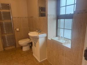 a bathroom with a sink and a toilet and a window at Dessie's in Magherasaul +23 photos