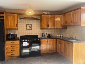 a kitchen with wooden cabinets and a black stove at Dessie's in Magherasaul