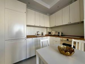 a kitchen with white cabinets and a white table at Kream Suite #Cosmopolis #Bucharest in Ştefăneştii de Sus