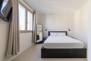 a white bedroom with a bed and a window at Relax Stay - Camere e Appartamenti con Giardino in Quartu Sant'Elena