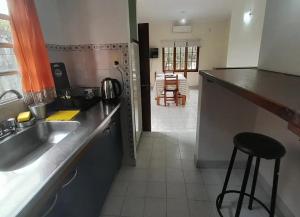 a kitchen with a sink and a counter with a stool at Temporario Elisa in Santa Fe