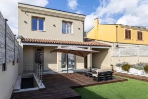 a house with a patio with an umbrella at Relax Stay - Camere e Appartamenti con Giardino in Quartu Sant'Elena