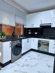 a kitchen with white cabinets and a washing machine at Lux Appartement Dahomy Beach in Bouznika