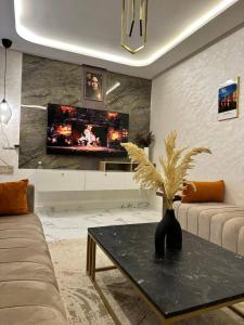 a living room with a table and a tv at Lux Appartement Dahomy Beach in Bouznika