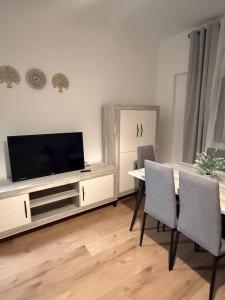 a living room with a table with chairs and a television at Alojamiento Baeza - Leones 9 A in Baeza