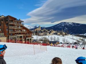 a group of people standing in the snow near a ski lodge at Entre lac et montagne in Les Angles