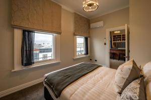 a bedroom with a bed and two windows at The Empire Hotel in Timaru