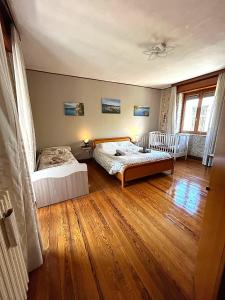 a bedroom with two beds and a wooden floor at Lago Maggiore Green House in Leggiuno