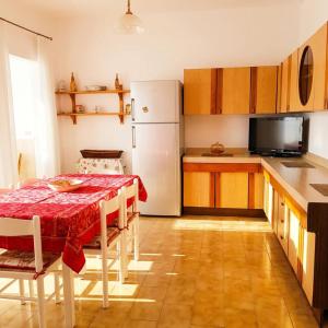 a kitchen with a table and a white refrigerator at Casa Aloe by My Home Apulia in Torre Lapillo