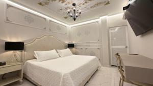 a white bedroom with a bed and a chandelier at Hotel Paris Carré in Valledupar