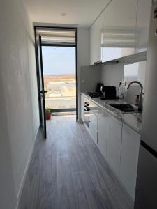 a kitchen with white cabinets and a large window at Ocean Palm Apartments II - Edifício Paradis- Cidadela in Praia