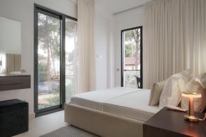 a bedroom with a bed and a large window at Poolside and Garden Apartments Golem Beach in Golem +64 photos