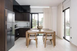 a kitchen with a table and chairs and a refrigerator at Poolside and Garden Apartments Golem Beach in Golem