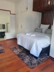 a bedroom with a bed with white sheets and a rug at Ludinz Self Catering Accommodation Bellville in Avondale