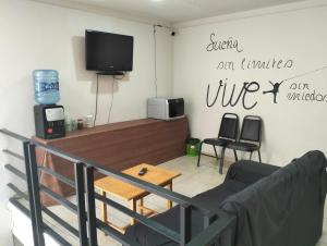 ein Wohnzimmer mit Fernseher, Tisch und Stühlen in der Unterkunft Hotel Morelia Nova in Morelia