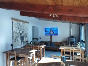 a living room with wooden tables and a tv on the wall at O Clarée in Val-des-Prés
