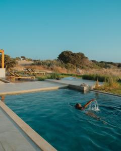 a person swimming in a swimming pool at Obsidian Suites Milos in Mytakas