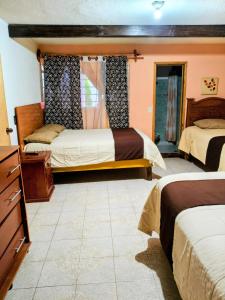 a bedroom with two beds and a dresser at El paraíso de Zacatlán DEPARTAMENTO con JARDÍN y Lumbrera, 11 personas in Zacatlán