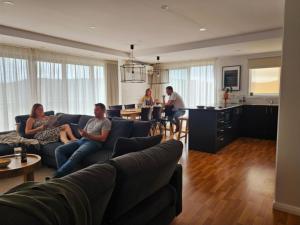 a group of people sitting on couches in a living room at Lake Kami Retreat - Jindabyne in Jindabyne
