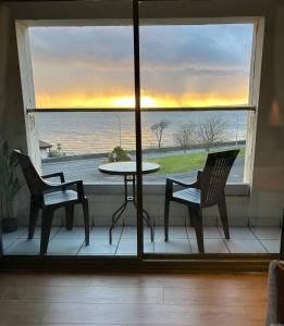 a table and chairs on a balcony with a view of the ocean at View of the Isles 2 in Largs