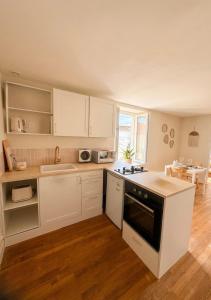 a kitchen with white cabinets and a stove top oven at Oasis proche du Futuroscope in Saint-Cyr
