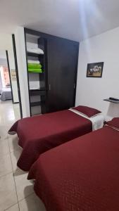two beds in a room with red sheets at Apto Rincón del Café -"Piscina-Parking-8min Parque Café 321-435-21-00" in Montenegro