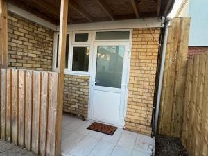 a white door on a brick building with a fence at Studio near Addenbrookes and Centre By Miller Residence in Cherry Hinton