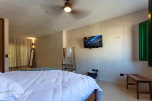 a bedroom with a white bed and a tv on the wall at Casa Calma 45 in Mérida