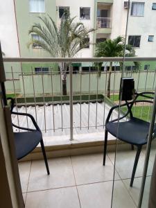 a balcony with two chairs and a palm tree at Apartamento vita bella in Porto Velho