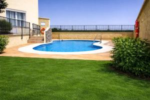 a small swimming pool in a yard with green grass at Apartamento PLAYANALA in Torrox Costa