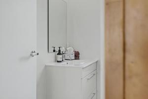 a white bathroom with a sink and a mirror at The Little Hive in Westport